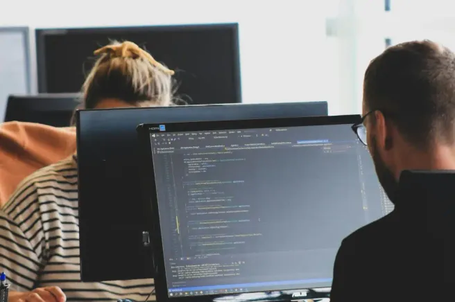 Developers reviewing code together at office monitors